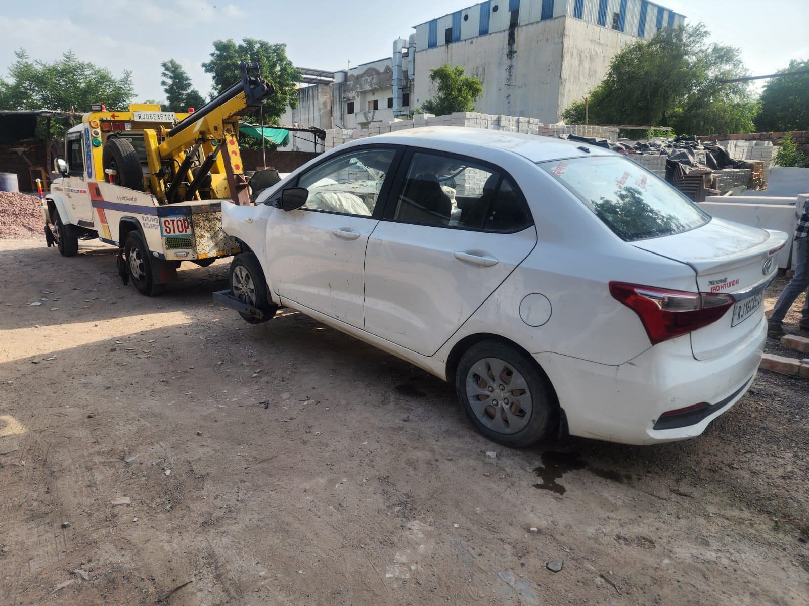 White sedan attached to a wheel-lift recovery truck